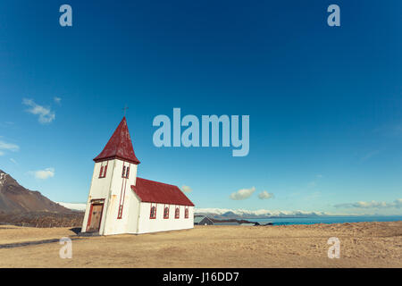 Un bianco chiesa collinare si trova in un campo oro con vedute del mare in Hellnar, Snaefellsnes (Snaefellsnes) penisola nella parte occidentale di Islanda Foto Stock