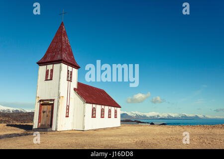 Un bianco chiesa collinare si trova in un campo oro con vedute del mare in Hellnar, Snaefellsnes (Snaefellsnes) penisola nella parte occidentale di Islanda Foto Stock