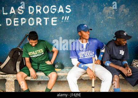 I giocatori di baseball a sedersi su una vecchia panca di legno in una piroga contro un azzurro parete dipinta Foto Stock