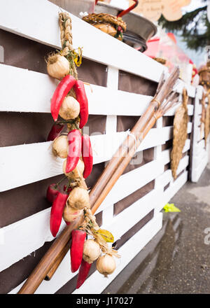 Aglio e Peperoncino appeso sul bianco sullo sfondo di legno all'esterno. Foto Stock