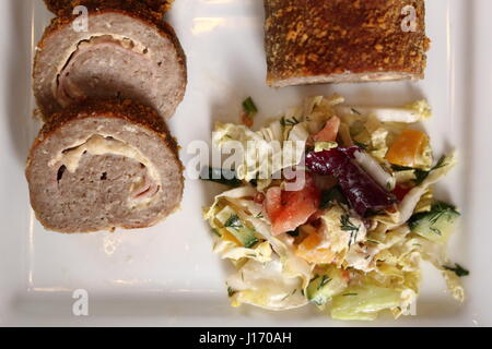 Involtino di carne con insalata sulla piastra. Carne arrotolata con ripieno di formaggio e prosciutto. Foto Stock