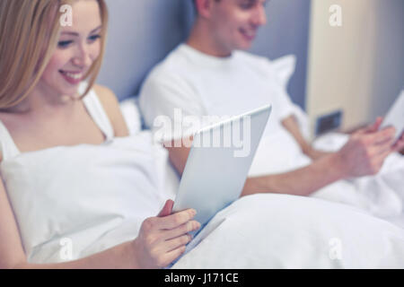 Coppia sorridente nel letto con tablet pc Foto Stock