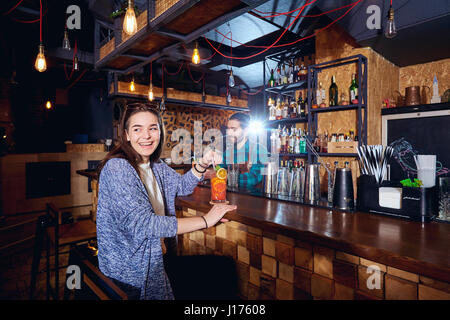 Un visitatore ragazza sorride nel bar con cocktail Foto Stock