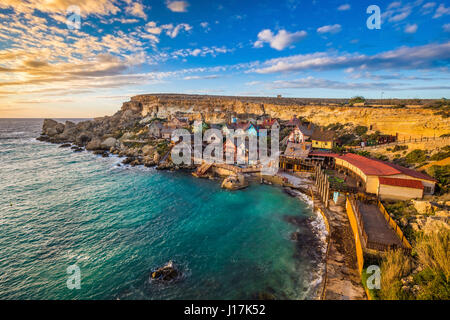 Il-Mellieha, Malta - Tramonto al famoso villaggio di Popeye In Anchor Bay. Questo villaggio è stato il set di Robert Altman il famoso film 'Popeye' con Robin W Foto Stock