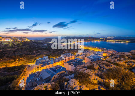 Il-Mellieha, Malta - Splendida vista dello skyline di Mellieha Bay dopo il tramonto con cielo blu e nuvole Foto Stock