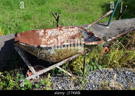 Vecchio rotto e rusty carriola abbandonato su un prato Foto Stock