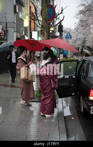 Geisha con ombrelloni tradizionale per arrivare in taxi su Kiyamachi-dori street in Higashiyama nr. Gion, Kyoto, Giappone Foto Stock