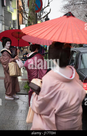 Geisha con ombrelloni tradizionale per arrivare in taxi su Kiyamachi-dori street in Higashiyama nr. Gion, Kyoto, Giappone Foto Stock