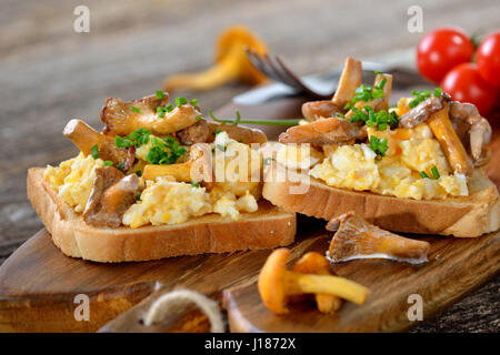 La prima colazione con uova strapazzate e fritte fresche i finferli su pane tostato Foto Stock