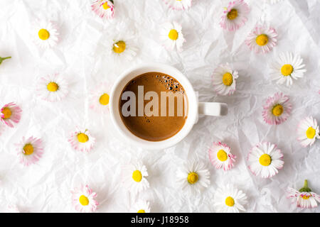 Tazza di caffè e daisy fiori sul tessuto bianco Foto Stock