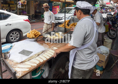 L'uomo la frittura churros su un street food cart in Chinatown, Bangkok, Thailandia Foto Stock