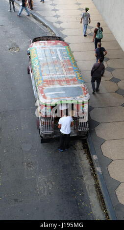 Un passeggero salendo su un Jeepney, un piccolo autobus che è una forma popolare di trasporto pubblico a Manila nelle Filippine Foto Stock