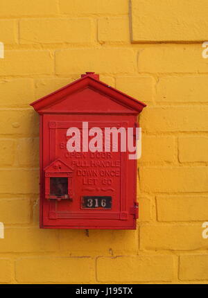 Un retro rosso fuoco allarme montato su un mattone giallo parete Foto Stock