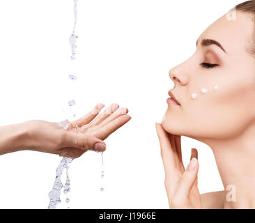 Donna faccia e versando acqua in mano. Foto Stock