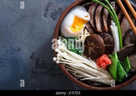 Duck tagliatelle con uovo e i funghi nel recipiente scuro sulla pietra nera sfondo texture Foto Stock