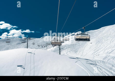 Impianti di risalita con sedili andando sulla soleggiata montagna Foto Stock