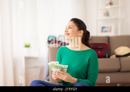 Donna felice con il denaro e la borsa da viaggio a casa Foto Stock