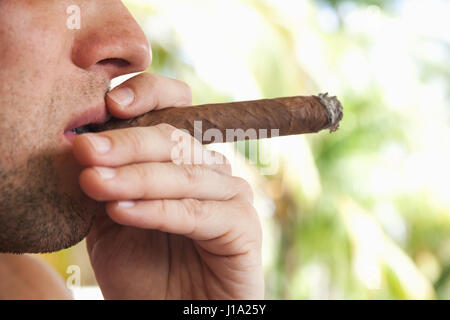 Giovane uomo europeo fuma sigari fatti a mano, closeup foto con messa a fuoco selettiva. Repubblica Dominicana Foto Stock