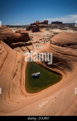 Natali Zollinger rilassante in un Materasso per piscina in una naturale buca piscina vicino a Moab, Utah. Foto Stock