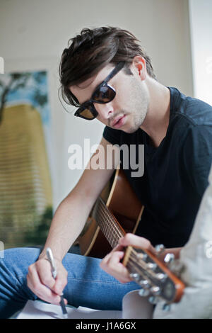 Giovane musicista scrivere canzoni su una chitarra acustica Foto Stock
