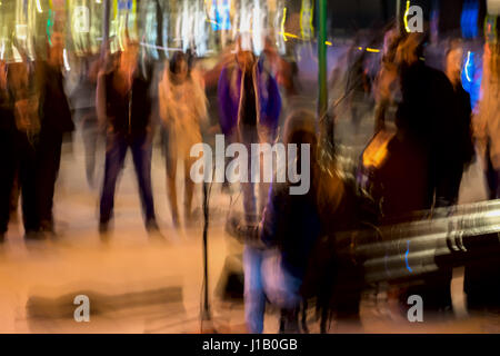 Abstract tono vintage moto, le prestazioni su strada, immagine sfocata di musicisti di strada, giovani spettatori. Urbano di notte la vita di strada, motion blur per uso in background Foto Stock