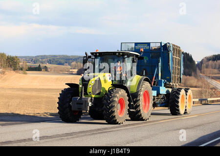 Salo, Finlandia - 13 aprile 2017: unità agricoltore moderno claas arion 640 trattore agricolo e edenhall 733 barbabietole mietitrice lungo strada su una bella serata di Foto Stock