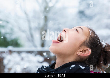 Razza mista ragazza cattura i fiocchi di neve sulla linguetta Foto Stock