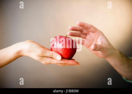 Mano di donna offrendo red apple per uomo Foto Stock