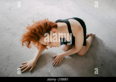 La donna caucasica inginocchiati sul pavimento Foto Stock