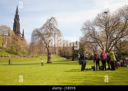 Princess Gardens, Edimburgo, Scozia, Regno Unito. Martedì 18 Aprile 2017 pomeriggio. Tempo soleggiato, vento leggero. Gruppo di viaggiatori con lo zaino in spalla seduto su ther sacchi sul th Foto Stock