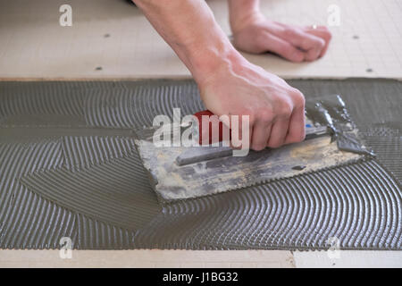 Piastrella setter che stabilisce thinset per un progetto di pannellizzazione nel corso di un importante casa di ristrutturazione. Foto Stock