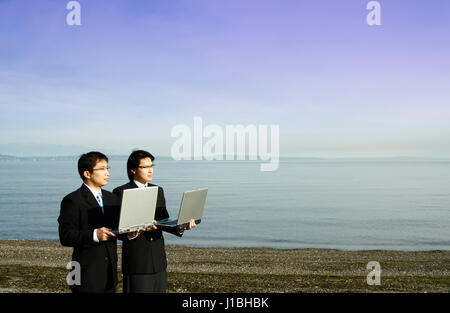 Due imprenditori che trasportano i loro notebook in spiaggia Foto Stock