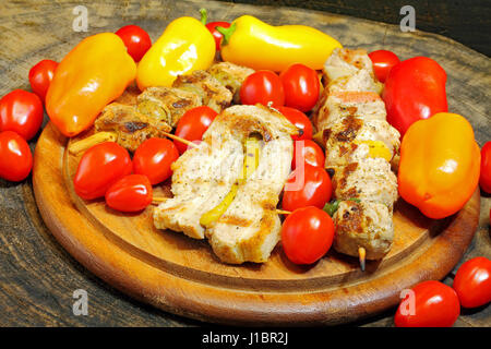 Grigliata di spiedini di carne con verdure su una tavola di legno Foto Stock