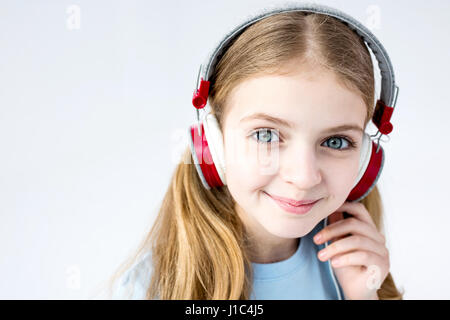 Adorabile ragazza ascolto di musica con cuffie in studio su bianco Foto Stock