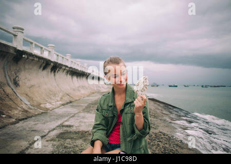 La donna caucasica guscio di contenimento a beach Foto Stock