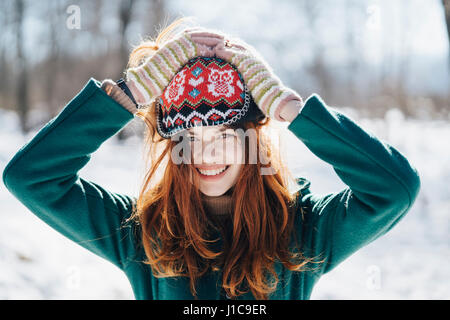 La donna caucasica holding hat sulla testa in inverno Foto Stock