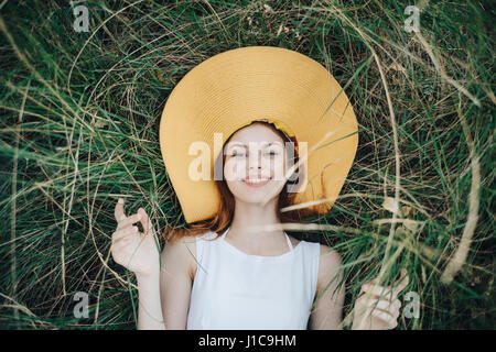 La donna caucasica indossando hat posa in erba Foto Stock