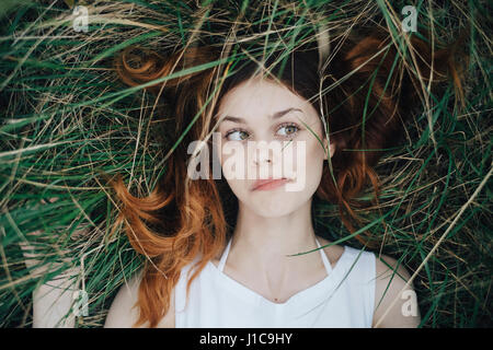 La donna caucasica posa in erba di soffiatura off capelli viso Foto Stock
