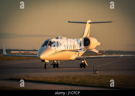 Business Jet rullaggio lungo la pista sul tramonto estivo Foto Stock