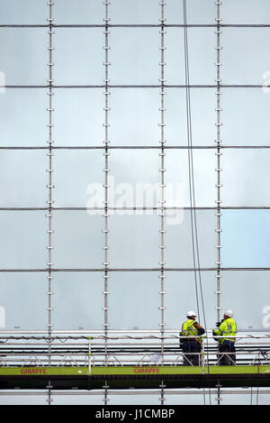 Operai su una piattaforma la riparazione di vetro frontale in costruzione Foto Stock