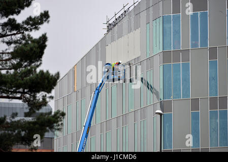 Operai in una cherry picker platform lavorando su un edificio moderno. Foto Stock