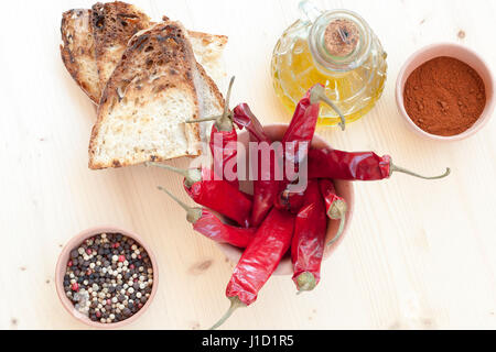 Peperoncino rosso, olio, il pane e il pepe in un vaso di argilla Foto Stock