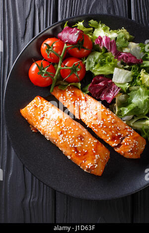 Deliziose vetrate di filetto di salmone con semi di sesamo e insalata di verdure fresche di close-up su un tavolo. Vista verticale da sopra Foto Stock