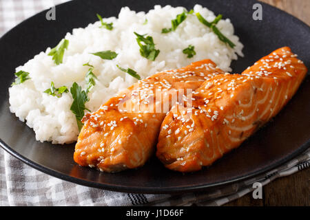 Salmone in smalto di miele con semi di sesamo e riso per guarnire close-up su una piastra orizzontale. Foto Stock
