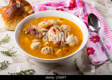 Polpettine di carne minestra sulla tavola con cucchiaio e pane Foto Stock