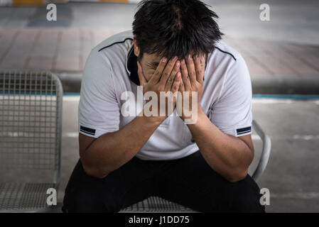 L'uomo licenziato dalla seduta di lavoro tenere la testa con la mano e preoccupata ha sottolineato l'espressione faccia al di fuori ufficio Foto Stock