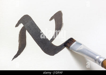 Spazzola piatta suggerimento scrivere lettera N in un stile uncial su carta bianca con inchiostro nero Foto Stock