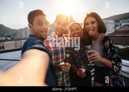 Gruppo di persone aventi una parte sul tetto facendo una selfie. Felice giovani amici prendendo ritratto di auto durante il party. Foto Stock