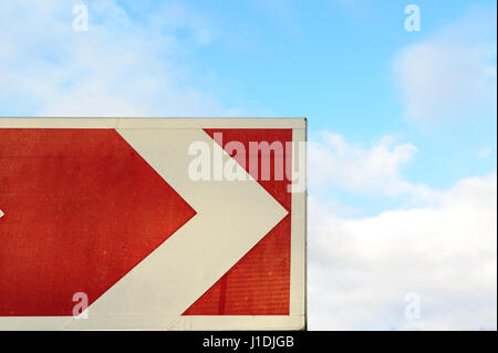 Freccia rossa puntatore sullo sfondo del cielo. Sul ciglio della strada e con il cielo nuvoloso. Road girare a segno. Vacanze Estate concetto di viaggio. Serpentina modo segno di attenzione. Autostrada svoltare a. Safe drive image Foto Stock