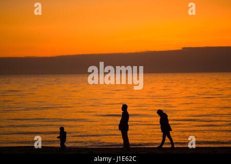 Aberystwyth Wales UK, giovedì 20 aprile 2017 UK Meteo: dopo un opaco e nebbioso per iniziare la giornata, una famiglia a piedi sulla spiaggia in Aberystwyth come dietro e poi la luce dorata del tramonto che illumina spettacolarmente su acque calme di Cardigan Bay sulla West Wales coast UK Photo credit: keith morris/Alamy Live News Foto Stock